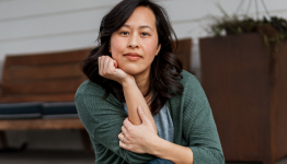 Woman sitting indoors with hand resting on chin