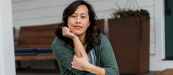Woman sitting indoors with hand resting on chin