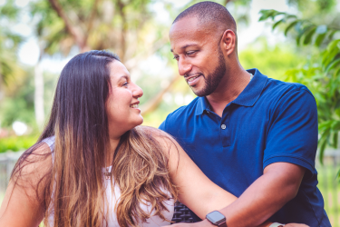 Man and woman sitting together outdoors and looking at each other