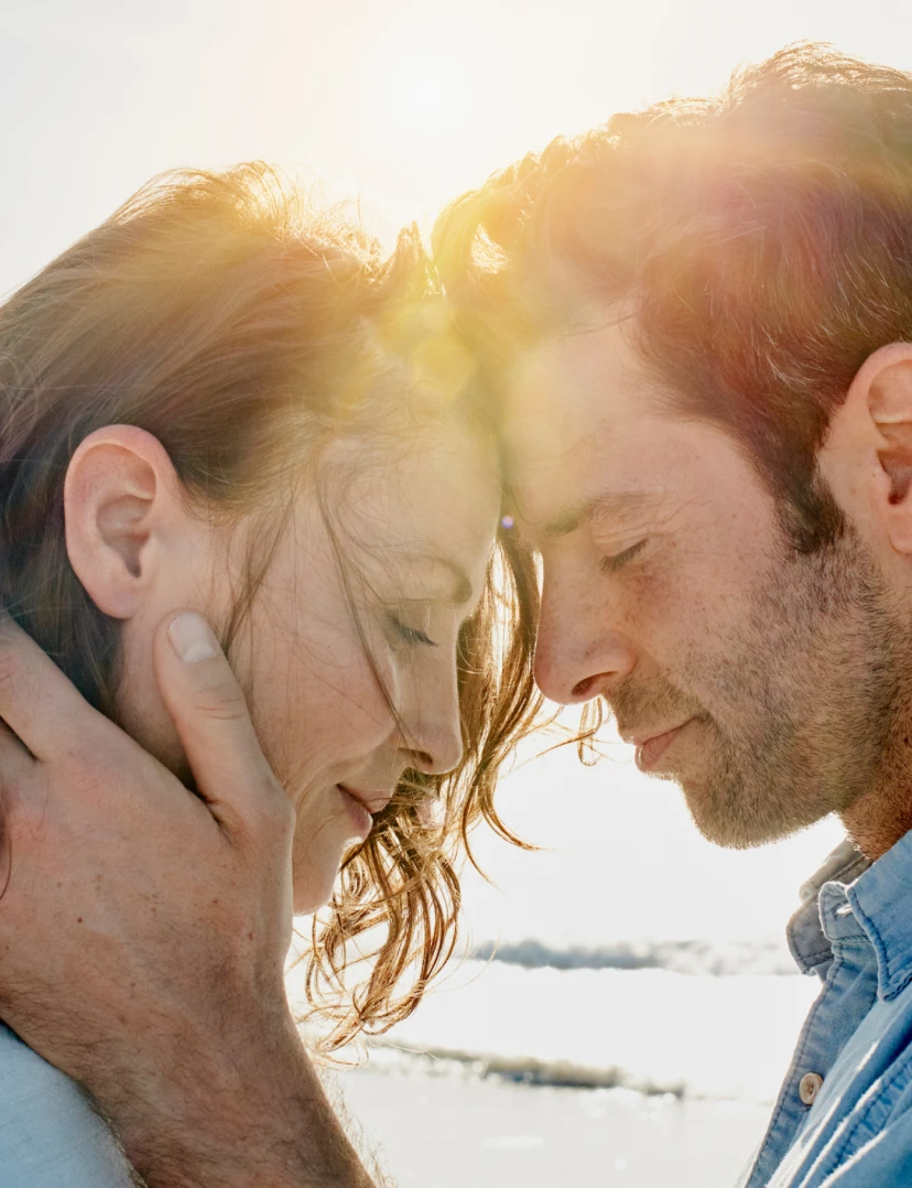 A man and woman lovingly put their heads together during a sunny day at the beach