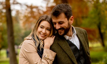 Couple embracing outdoors with autumn foliage