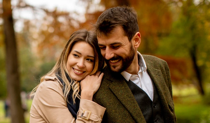 Couple embracing outdoors with autumn foliage