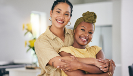 Two women embracing and smiling indoors