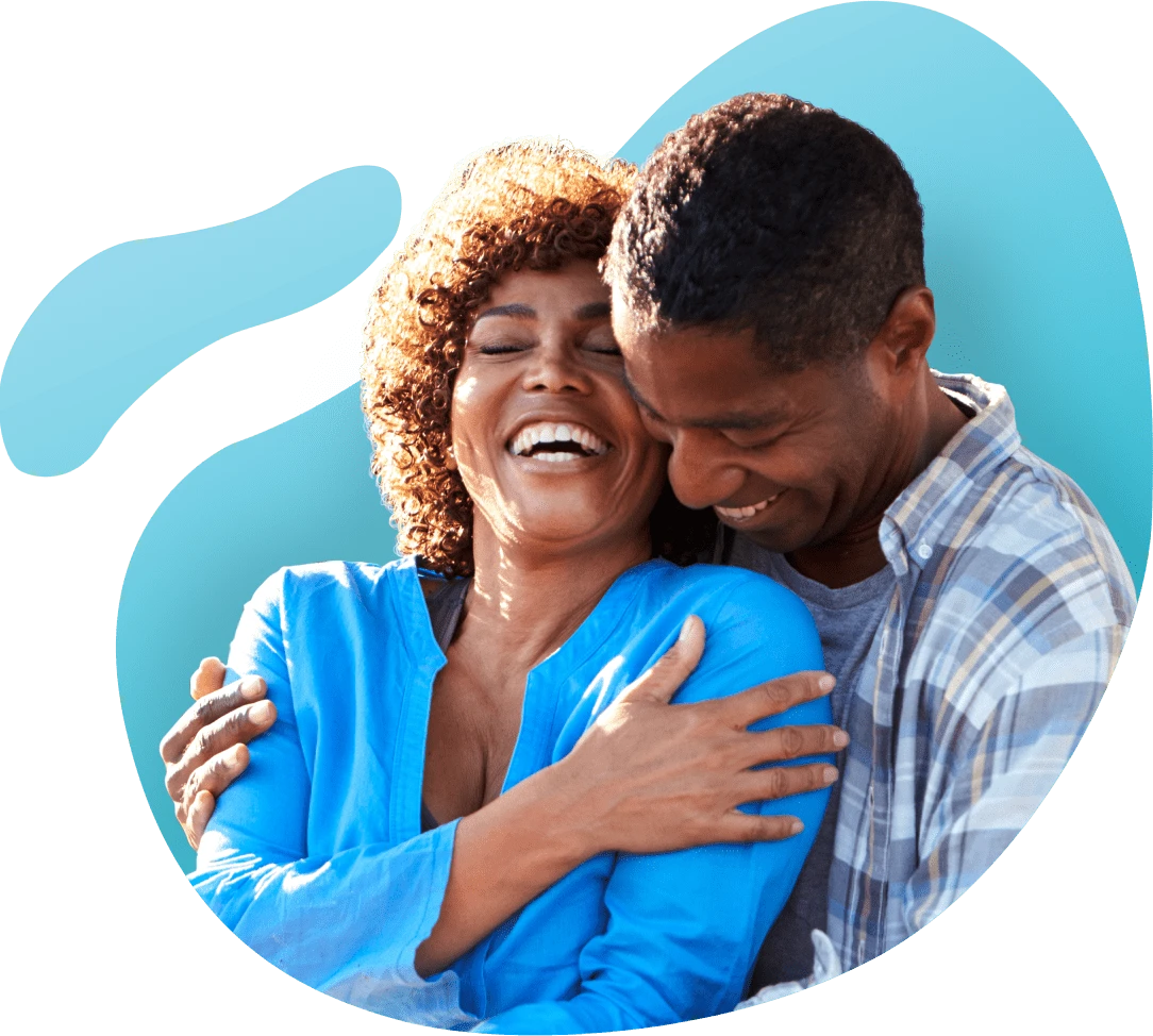 A couple embraces and laughs against a blue background
